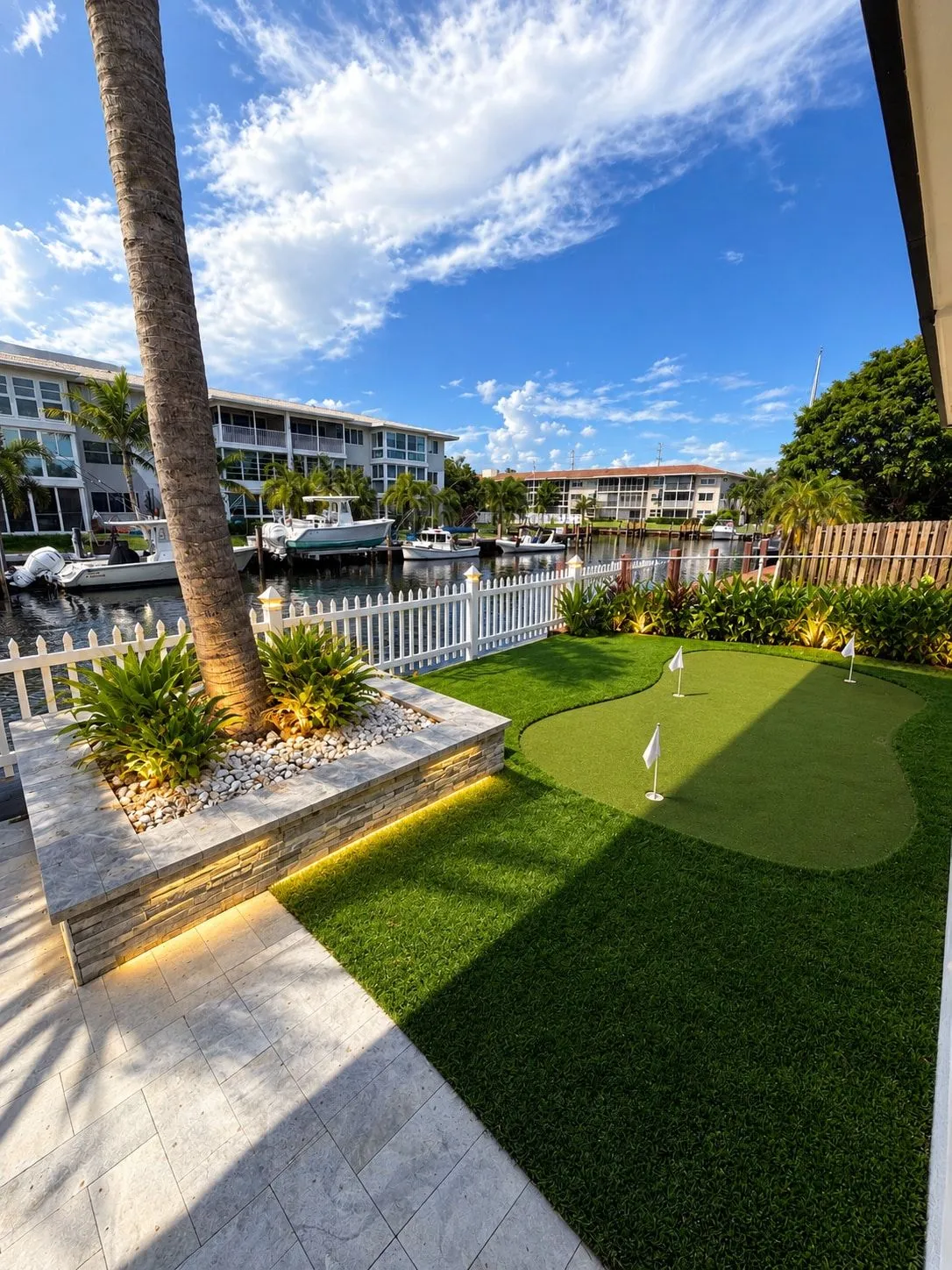 Casa Palm Breeze — A putting green, a picket fence, and the canal at the end of the garden.